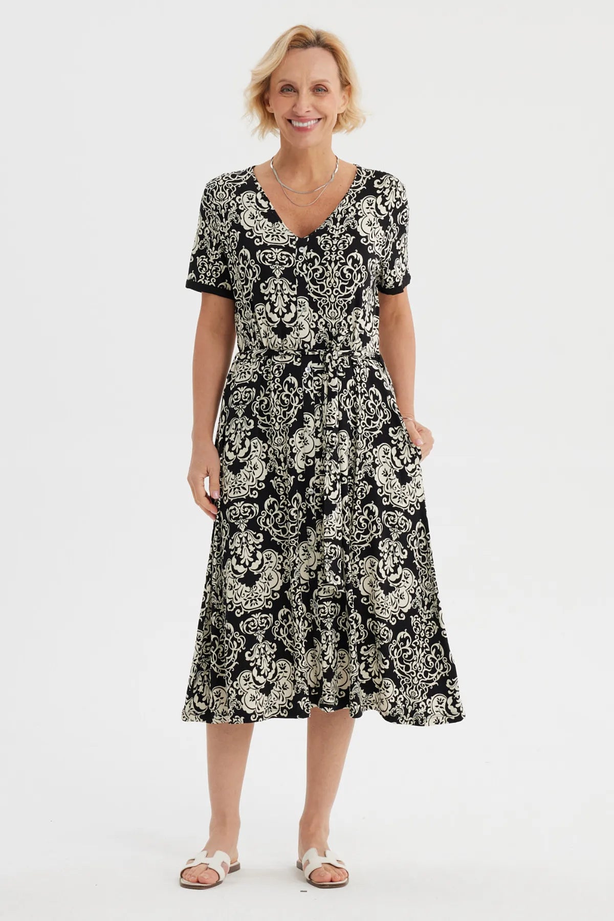 Vestido negro de mujer con estampado blanco de arabescos estilo vintage que cubre toda la prenda hasta las rodillas