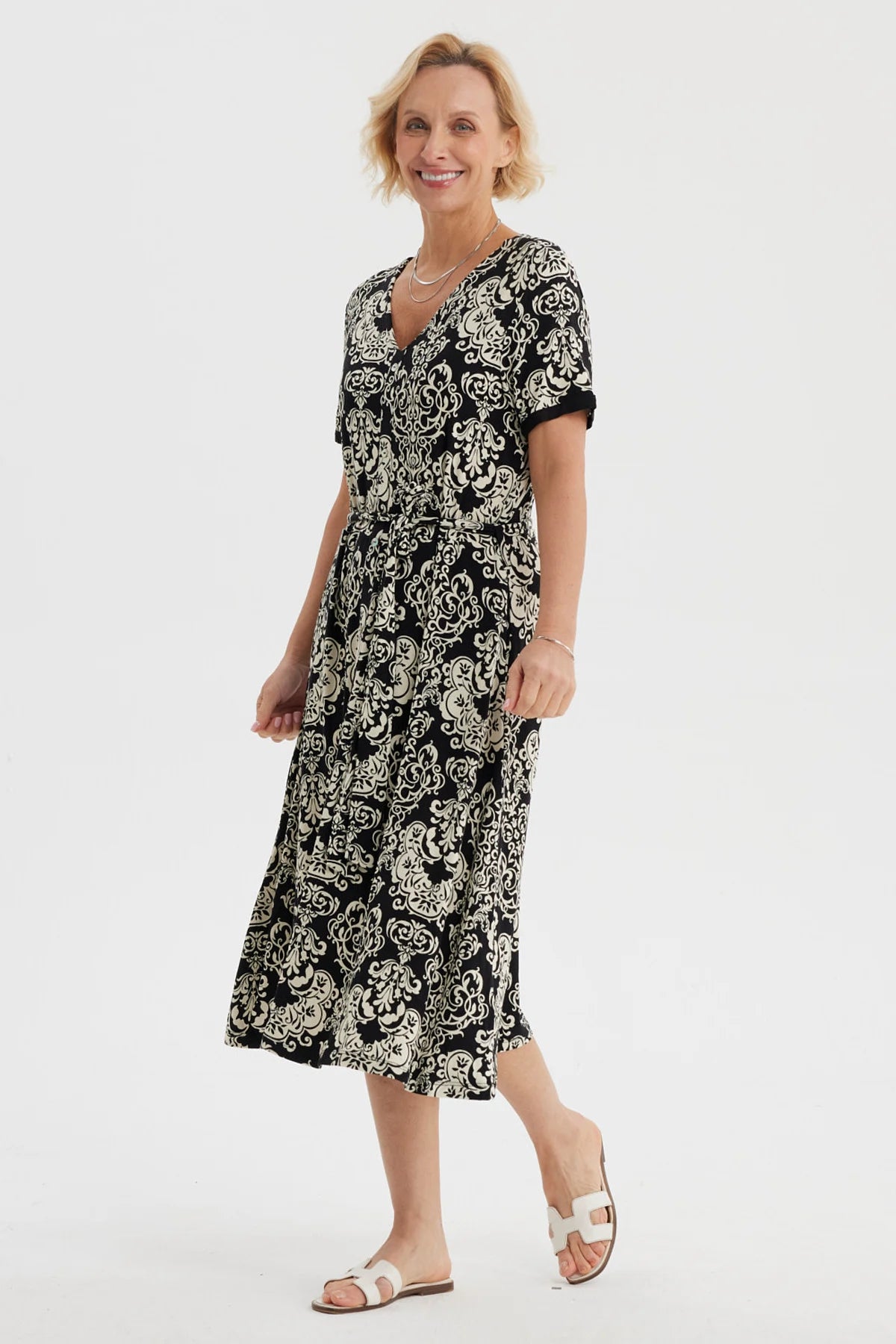 Vestido negro de mujer con estampado blanco de arabescos estilo vintage que cubre toda la prenda hasta las rodillas