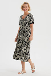 Vestido negro de mujer con estampado blanco de arabescos estilo vintage que cubre toda la prenda hasta las rodillas