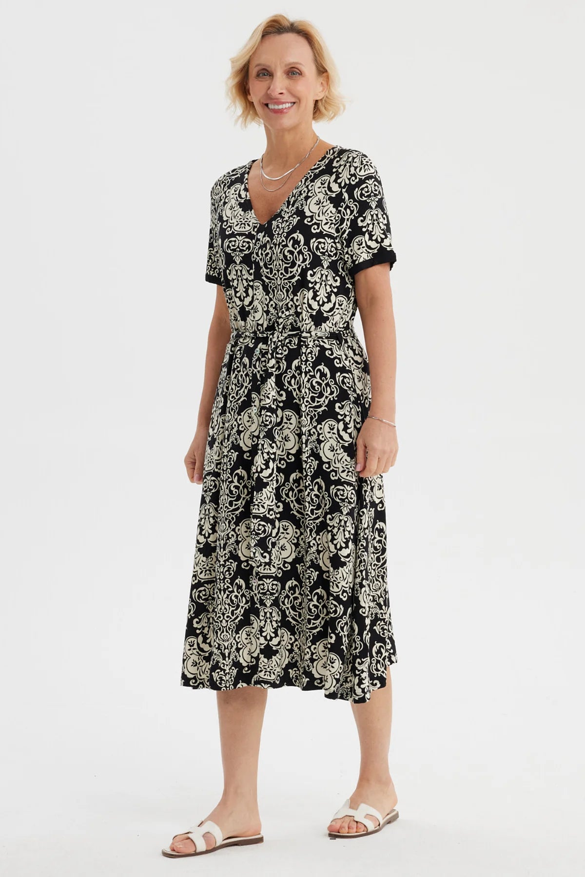 Vestido negro de mujer con estampado blanco de arabescos estilo vintage que cubre toda la prenda hasta las rodillas