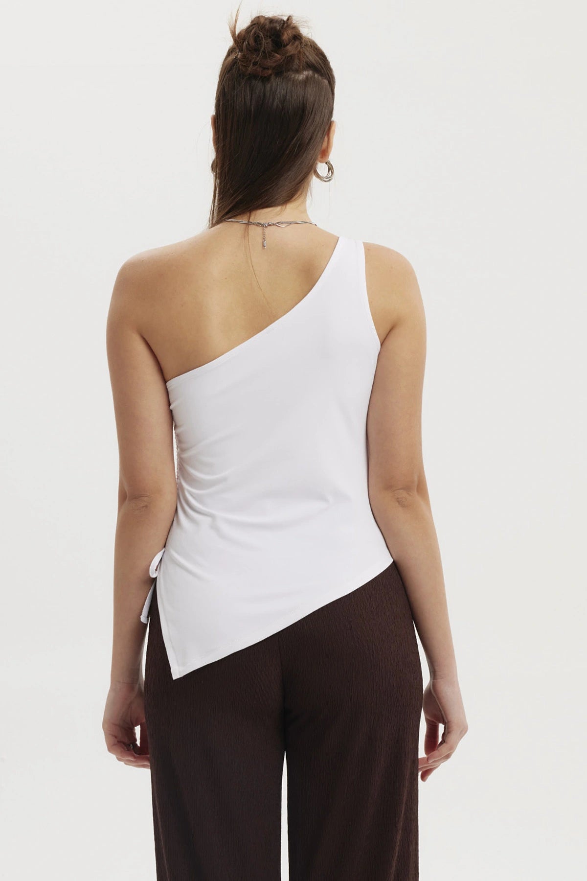 Polera asimétrica blanca de mujer con escote de un solo hombro y detalle de lazo lateral diseño liso
