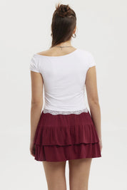 Polera asimétrica blanca con detalle de encaje en el bajo ajustada al cuerpo lisa y sin estampado