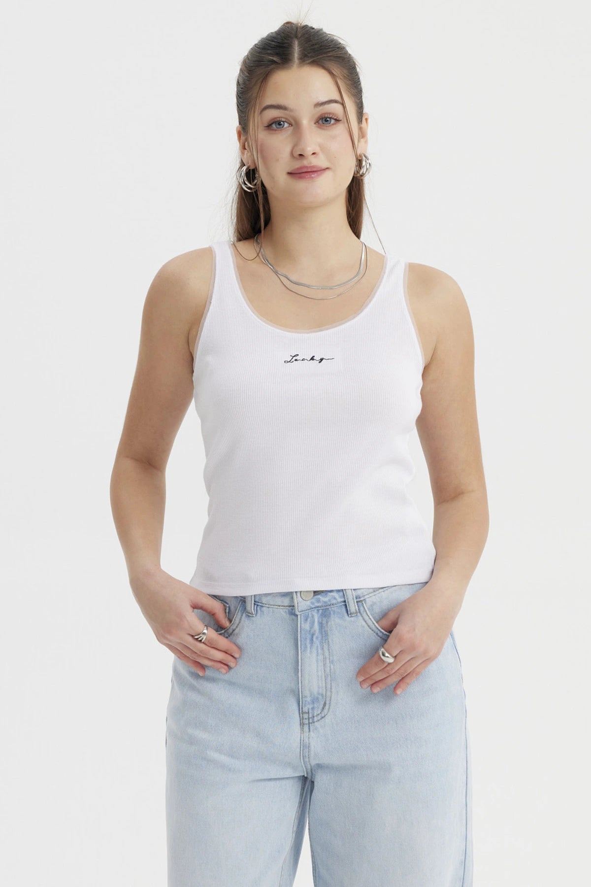Polera blanca de mujer sin mangas con texto 'Lucky' en el centro de estilo minimalista y corte ajustado
