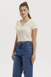 Polera crema de mujer con vuelos en el cuello y botones frontales diseño acanalado lisa elegante y casual