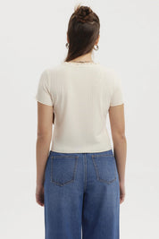 Polera crema de mujer con vuelos en el cuello y botones frontales diseño acanalado lisa elegante y casual