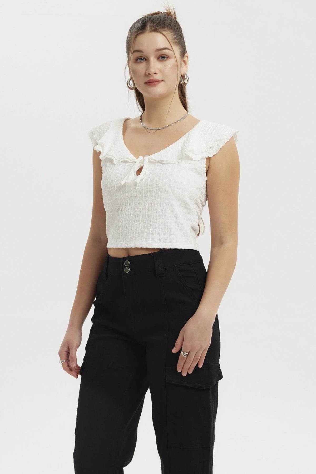 Polera blanca de mujer con cuello de vuelos y detalle de lazo en el centro diseño liso elegante y femenino