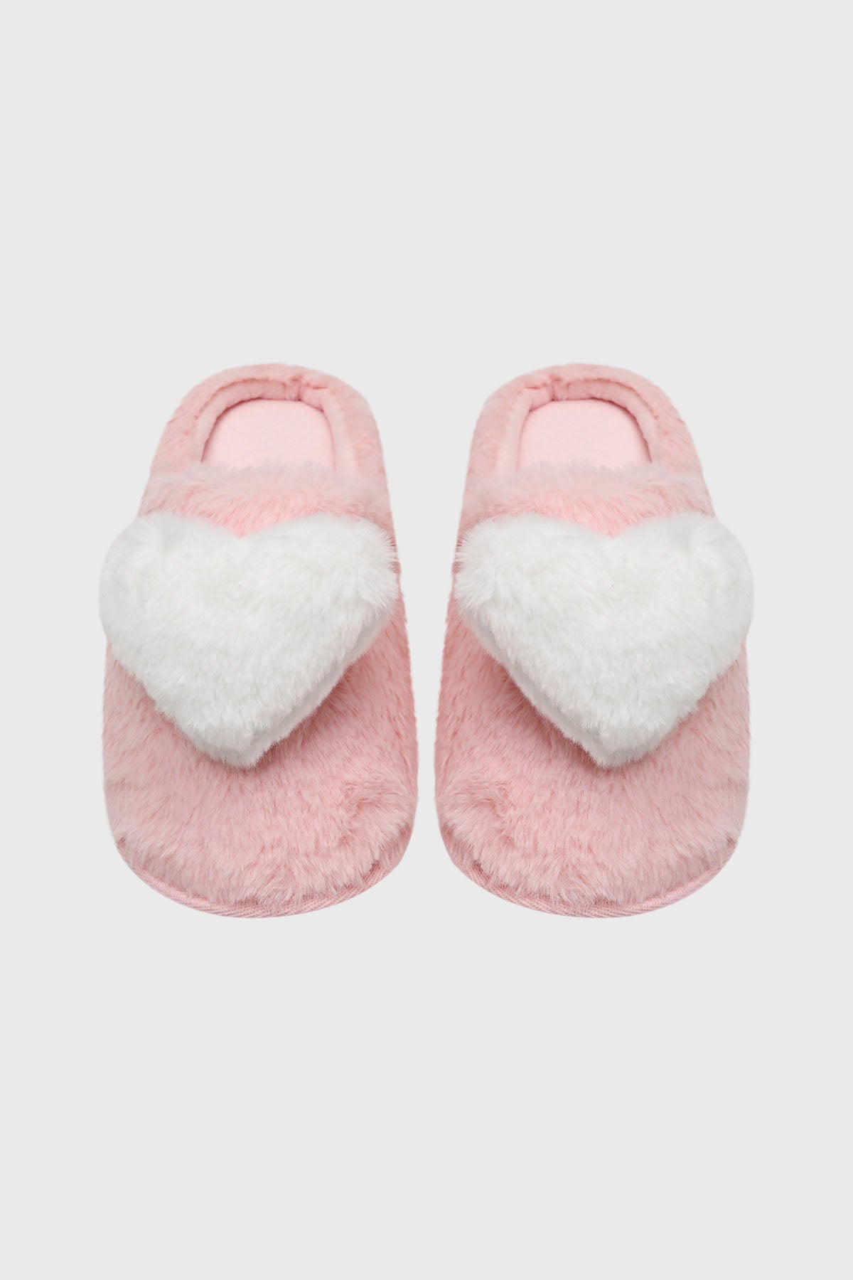 Pantuflas de mujer rosadas con un gran corazón blanco esponjoso en el empeine diseño acogedor y divertido