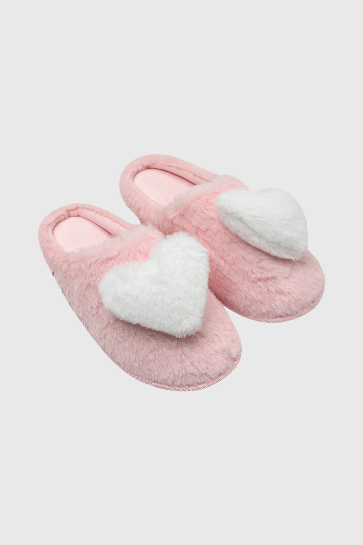 Pantuflas de mujer rosadas con un gran corazón blanco esponjoso en el empeine diseño acogedor y divertido