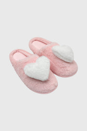 Pantuflas de mujer rosadas con un gran corazón blanco esponjoso en el empeine diseño acogedor y divertido