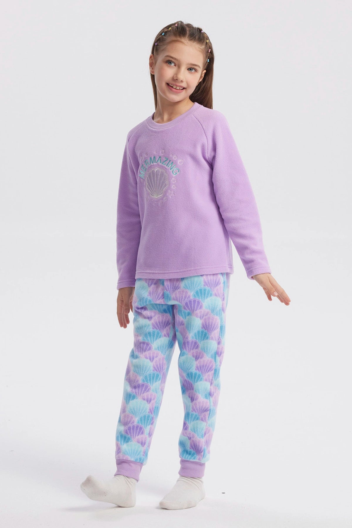 Pijama de niña color lila con polera de concha y texto "Mermazing" al frente pantalón con diseño de conchas en azul y lila