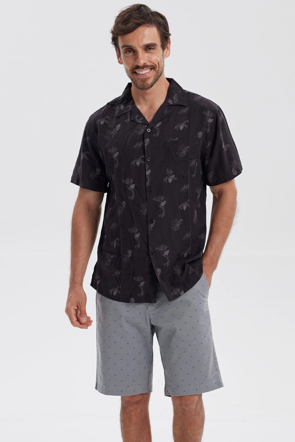 Camisa negra de hombre con estampado de hojas y piñas en gris de estilo tropical por toda la prenda
