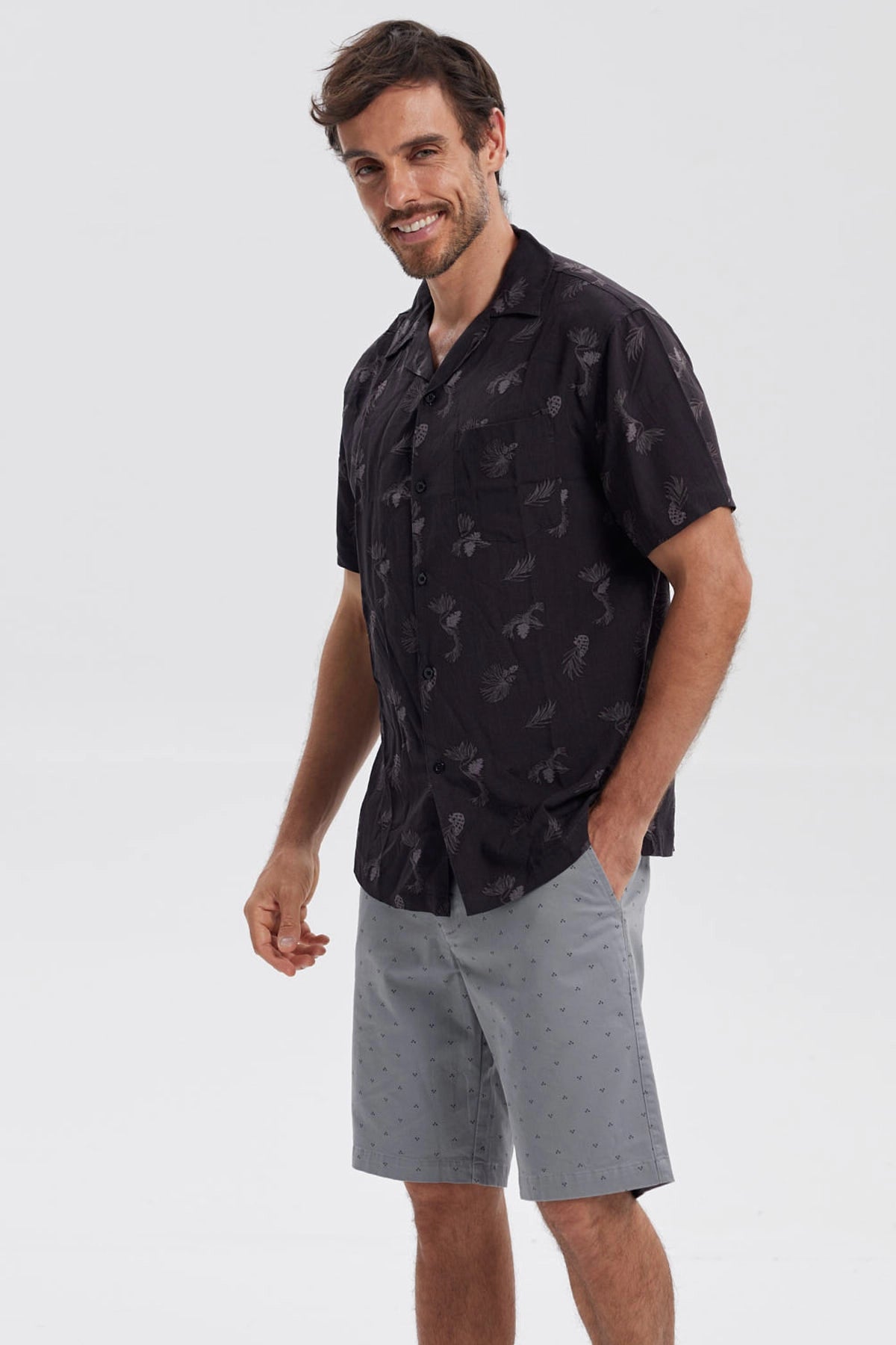 Camisa negra de hombre con estampado de hojas y piñas en gris de estilo tropical por toda la prenda