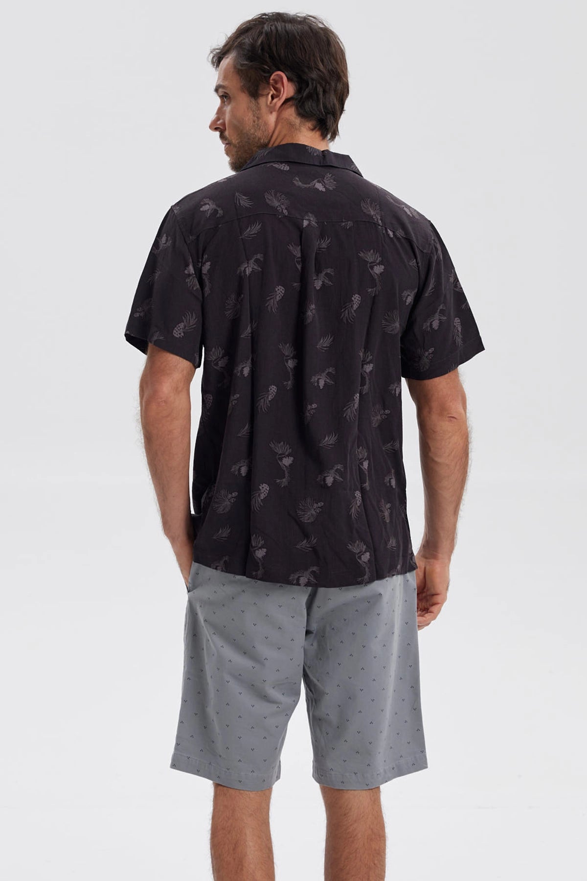 Camisa negra de hombre con estampado de hojas y piñas en gris de estilo tropical por toda la prenda