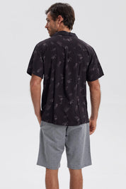 Camisa negra de hombre con estampado de hojas y piñas en gris de estilo tropical por toda la prenda