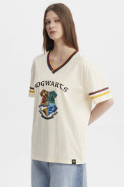 Polera beige de mujer con cuello en V y bordes a rayas con el escudo de Hogwarts grande en el centro estilo clásico
