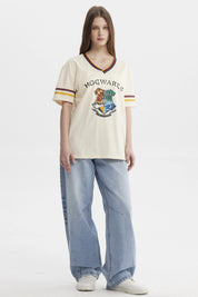 Polera beige de mujer con cuello en V y bordes a rayas con el escudo de Hogwarts grande en el centro estilo clásico