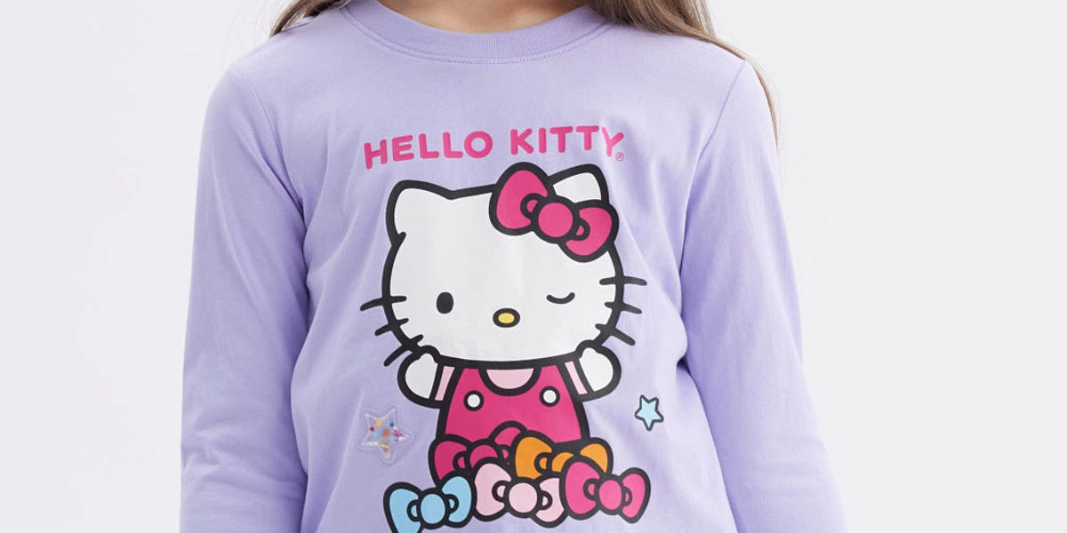 Polera niña lila con Hello Kitty en el frente con moños de colores y texto Hello Kitty en estilo gráfico animado