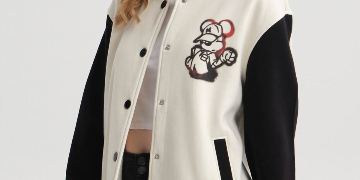 Polerón beige mujer con estampado de Mickey Mouse en el pecho y mangas negras estilo varsity