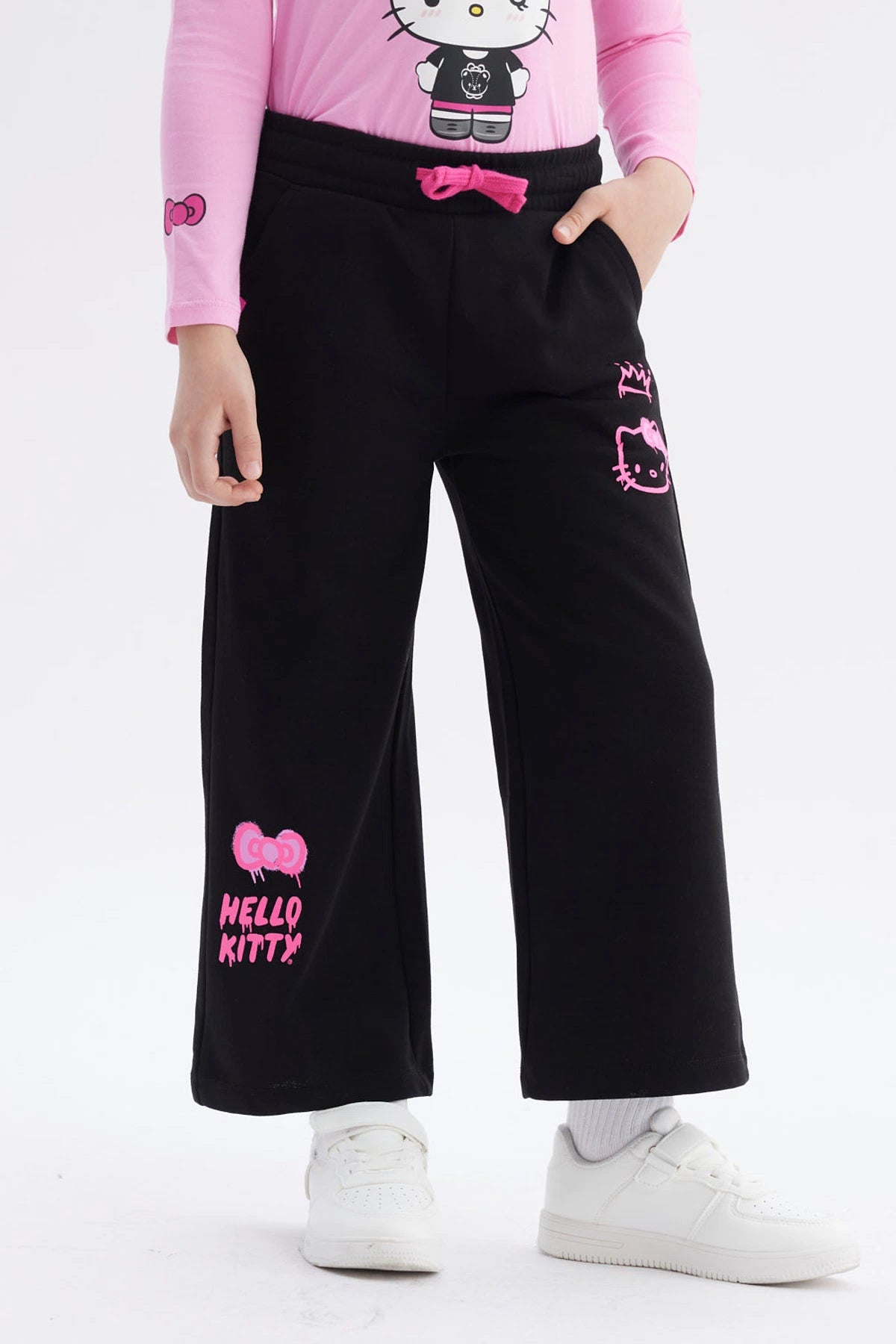 Pantalón buzo negro niña con estampado rosa de Hello Kitty en pierna izquierda estilo gráfico grande y texto Hello Kitty