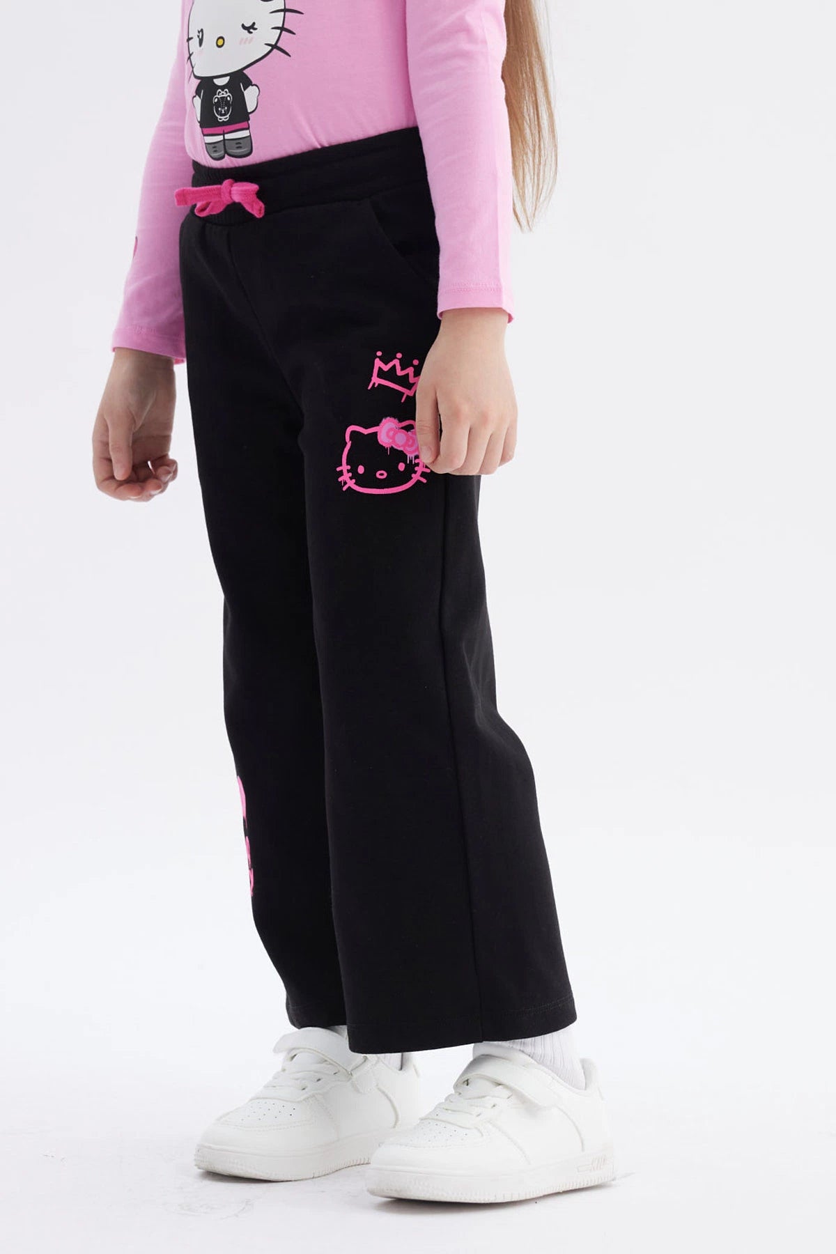 Pantalón buzo negro niña con estampado rosa de Hello Kitty en pierna izquierda estilo gráfico grande y texto Hello Kitty