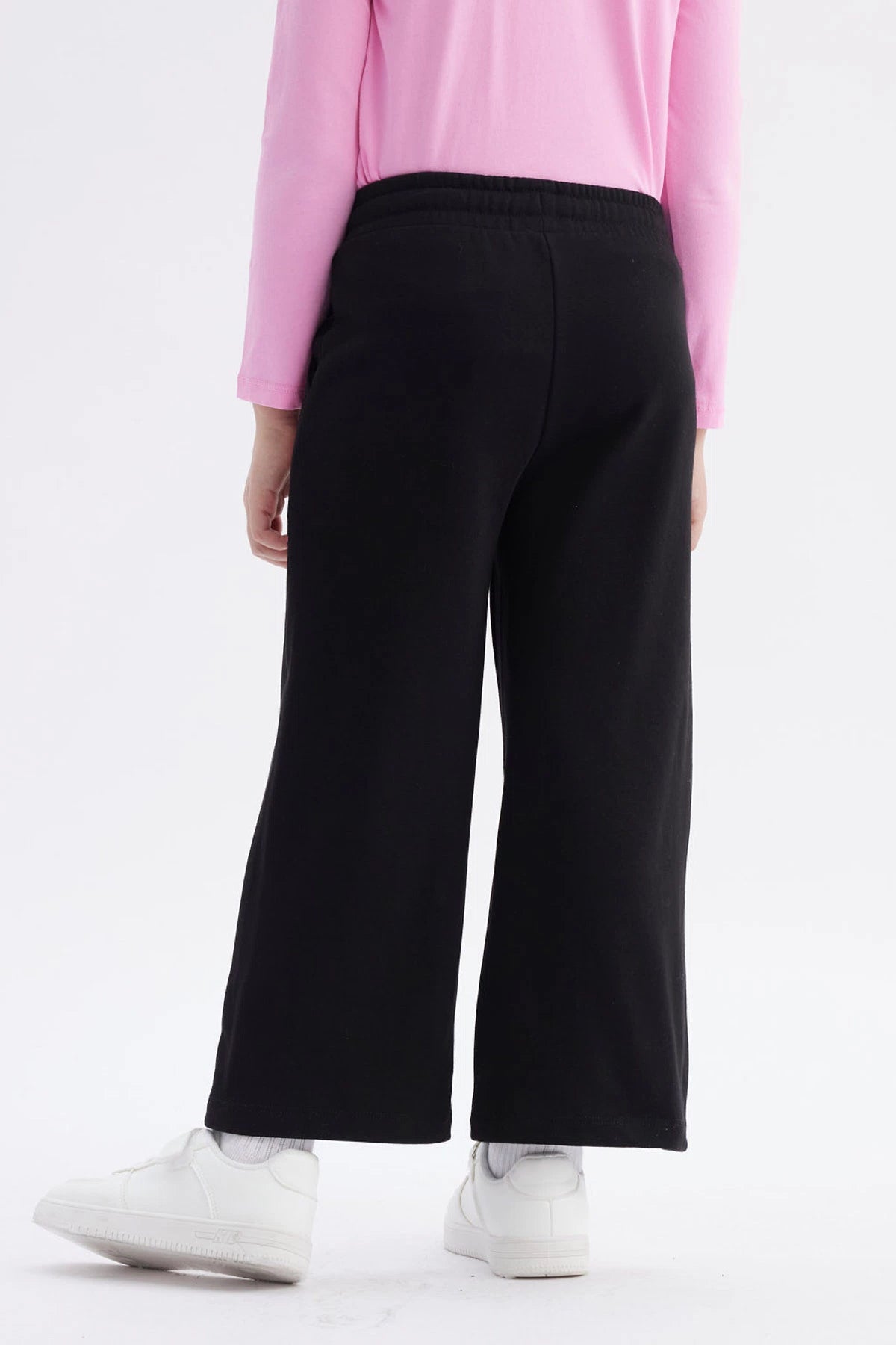 Pantalón buzo negro niña con estampado rosa de Hello Kitty en pierna izquierda estilo gráfico grande y texto Hello Kitty