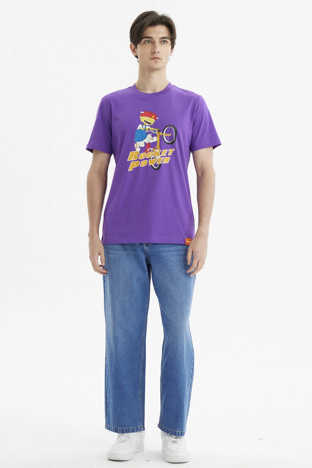Polera morada de hombre con personaje animado en bicicleta y texto Rocket Power al frente estilo caricatura