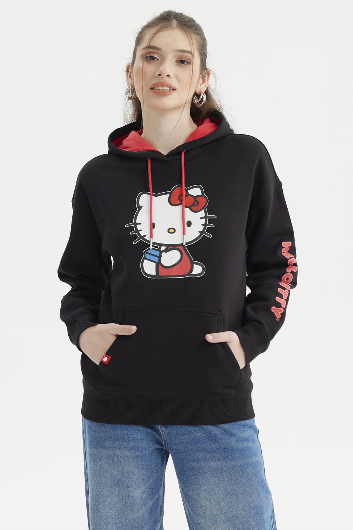 Polerón negro de mujer con capucha roja y estampado central de Hello Kitty sosteniendo una taza en estilo cartoon