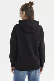 Polerón negro de mujer con capucha roja y estampado central de Hello Kitty sosteniendo una taza en estilo cartoon