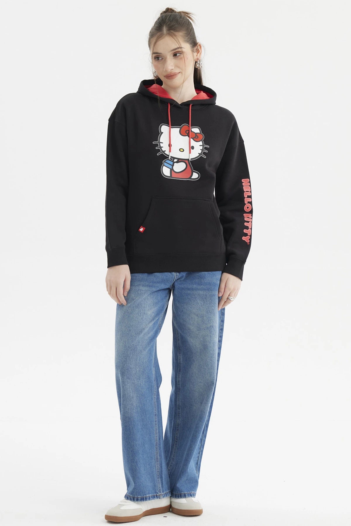 Polerón negro de mujer con capucha roja y estampado central de Hello Kitty sosteniendo una taza en estilo cartoon