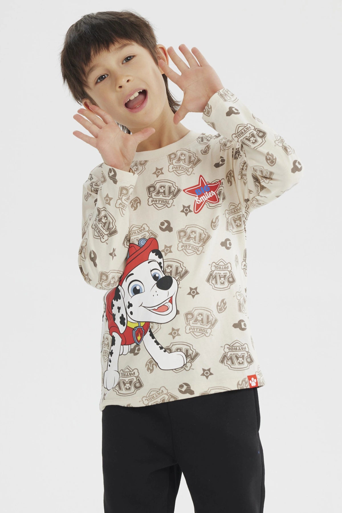 Polera beige para niño con estampa grande de Marshall de Paw Patrol en el frente estilo dibujo animado y fondo con logos