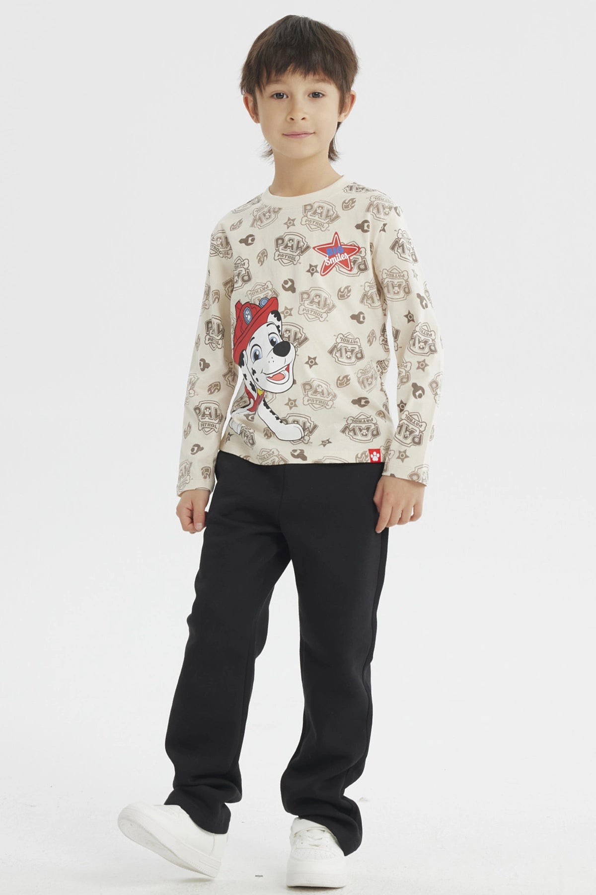 Polera beige para niño con estampa grande de Marshall de Paw Patrol en el frente estilo dibujo animado y fondo con logos