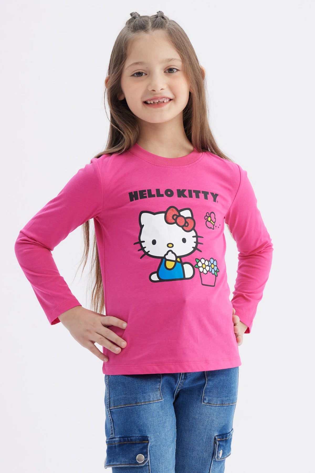 Polera niña rosada de manga larga con Hello Kitty grande al centro sosteniendo una regadera junto a flores