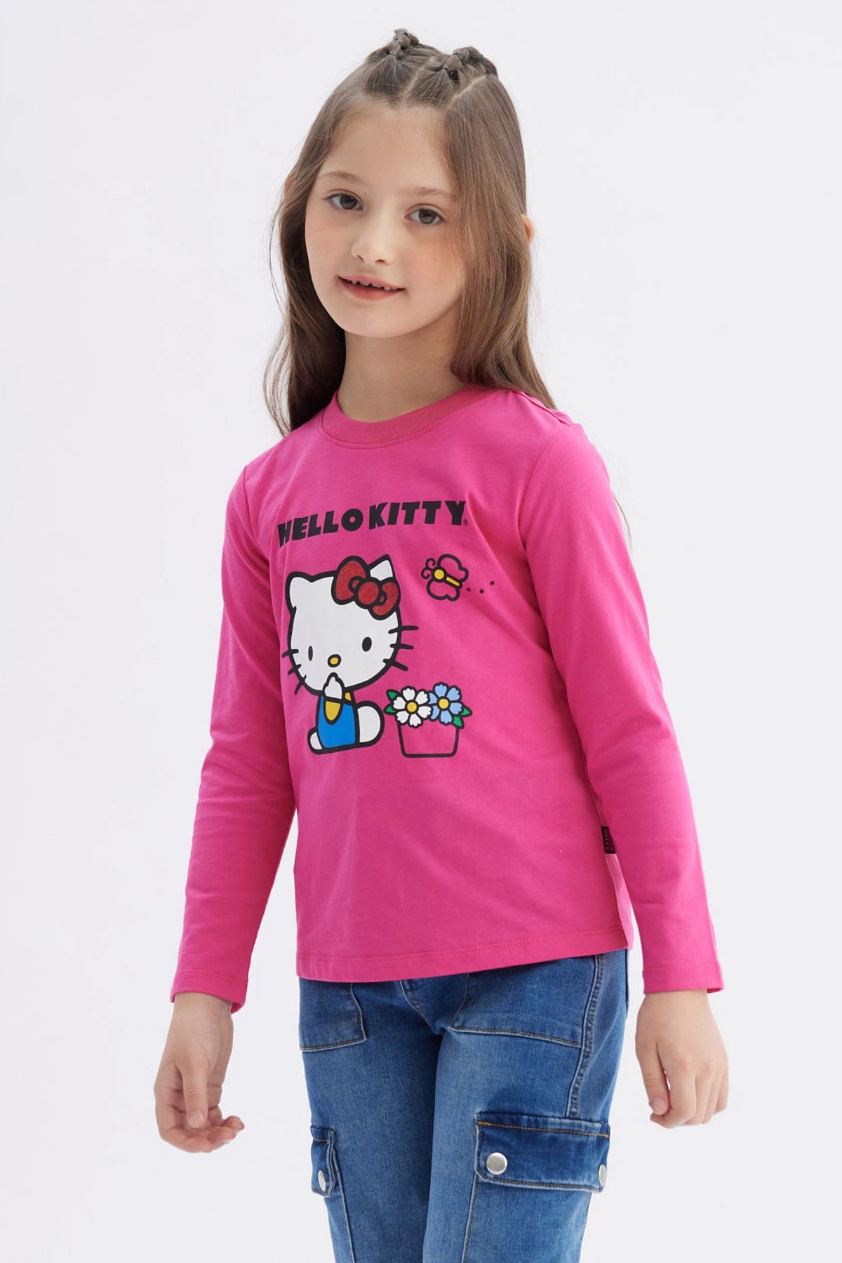 Polera niña rosada de manga larga con Hello Kitty grande al centro sosteniendo una regadera junto a flores