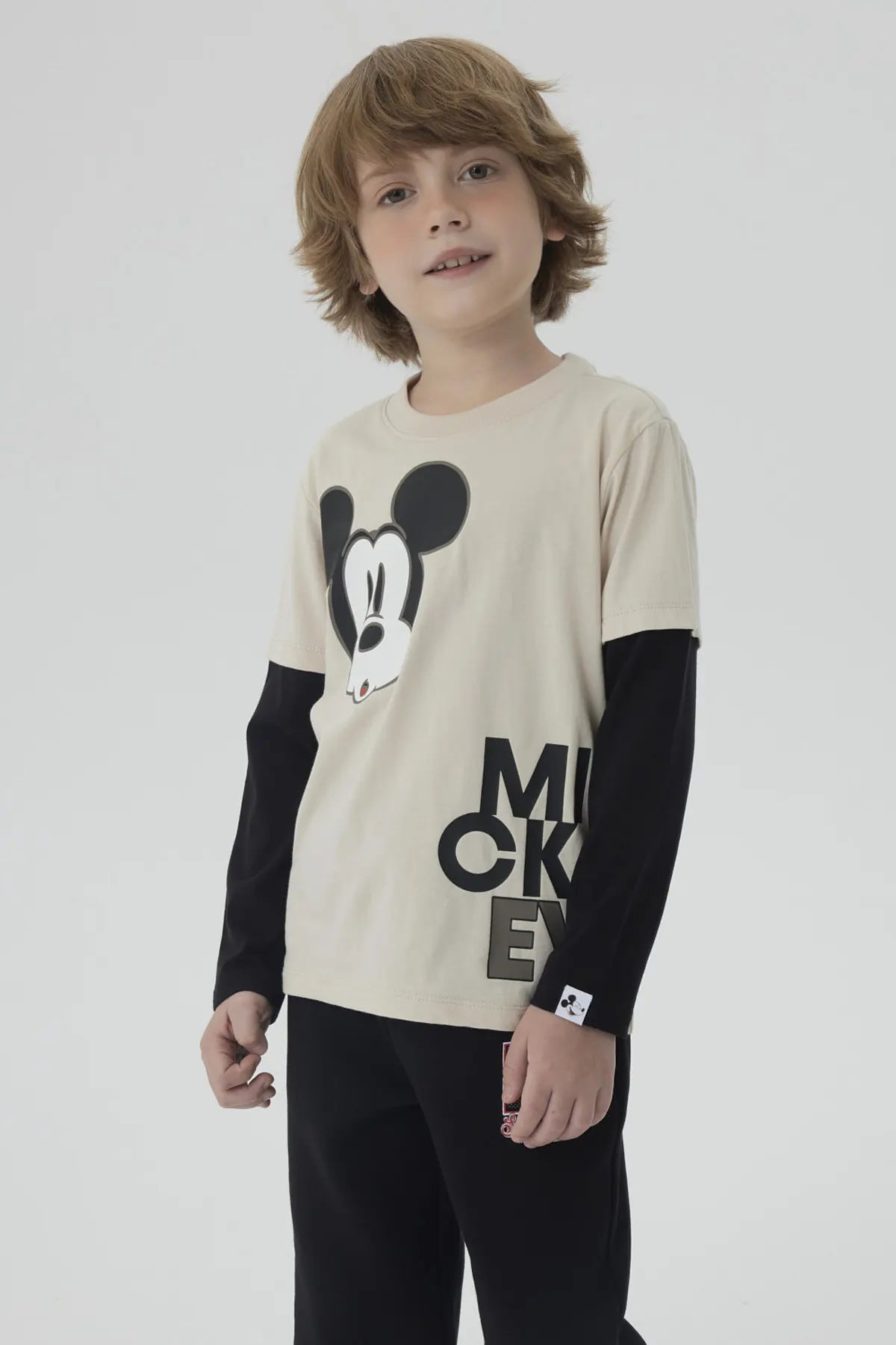 Polera de niño caqui con imagen de Mickey Mouse en el centro y texto MICKEY abajo en letras grandes negras