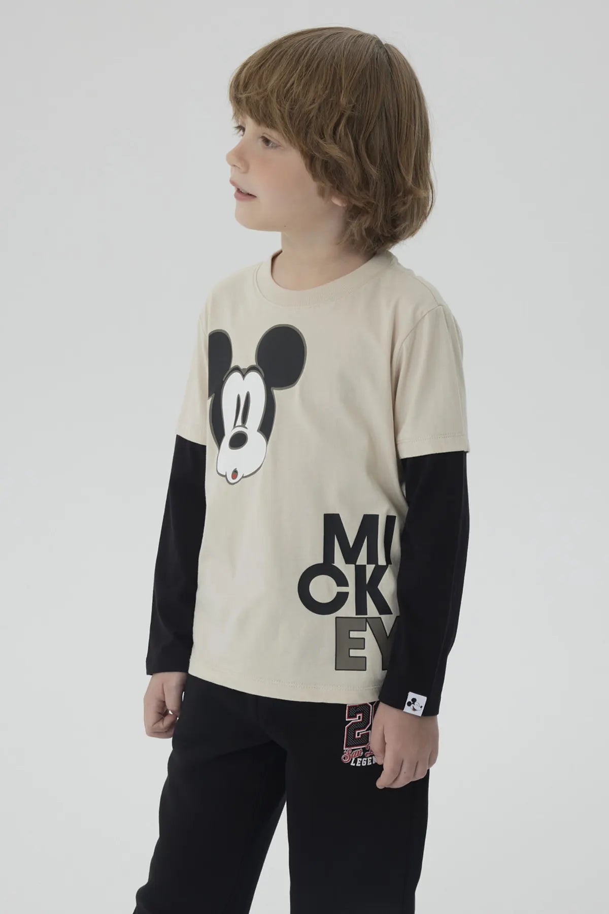 Polera de niño caqui con imagen de Mickey Mouse en el centro y texto MICKEY abajo en letras grandes negras