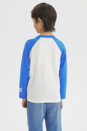 Polera crudo de niño con mangas azules y estampa de Bluey jugando fútbol al frente en estilo animado