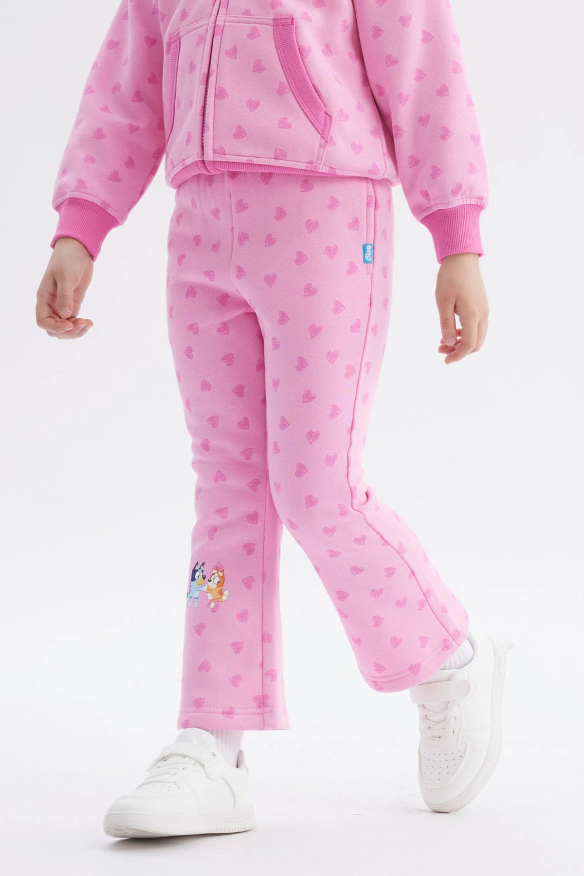 Pantalón buzo rosado de niña con corazones estampados y personajes Bluey en la pierna izquierda estilo animado
