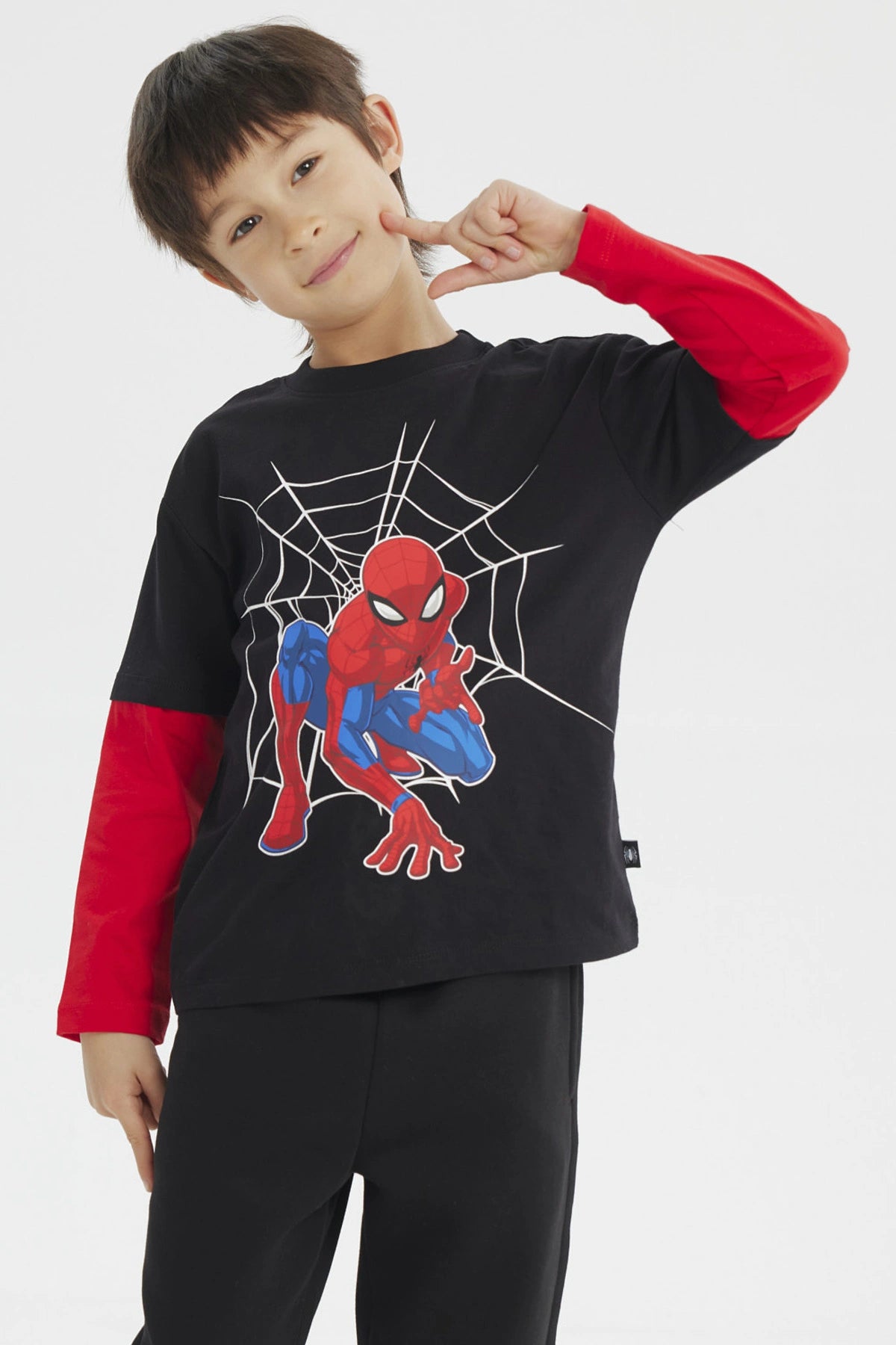Polera niño negra con mangas rojas y estampado de Spiderman en acción sobre telaraña en el centro estilo cómic