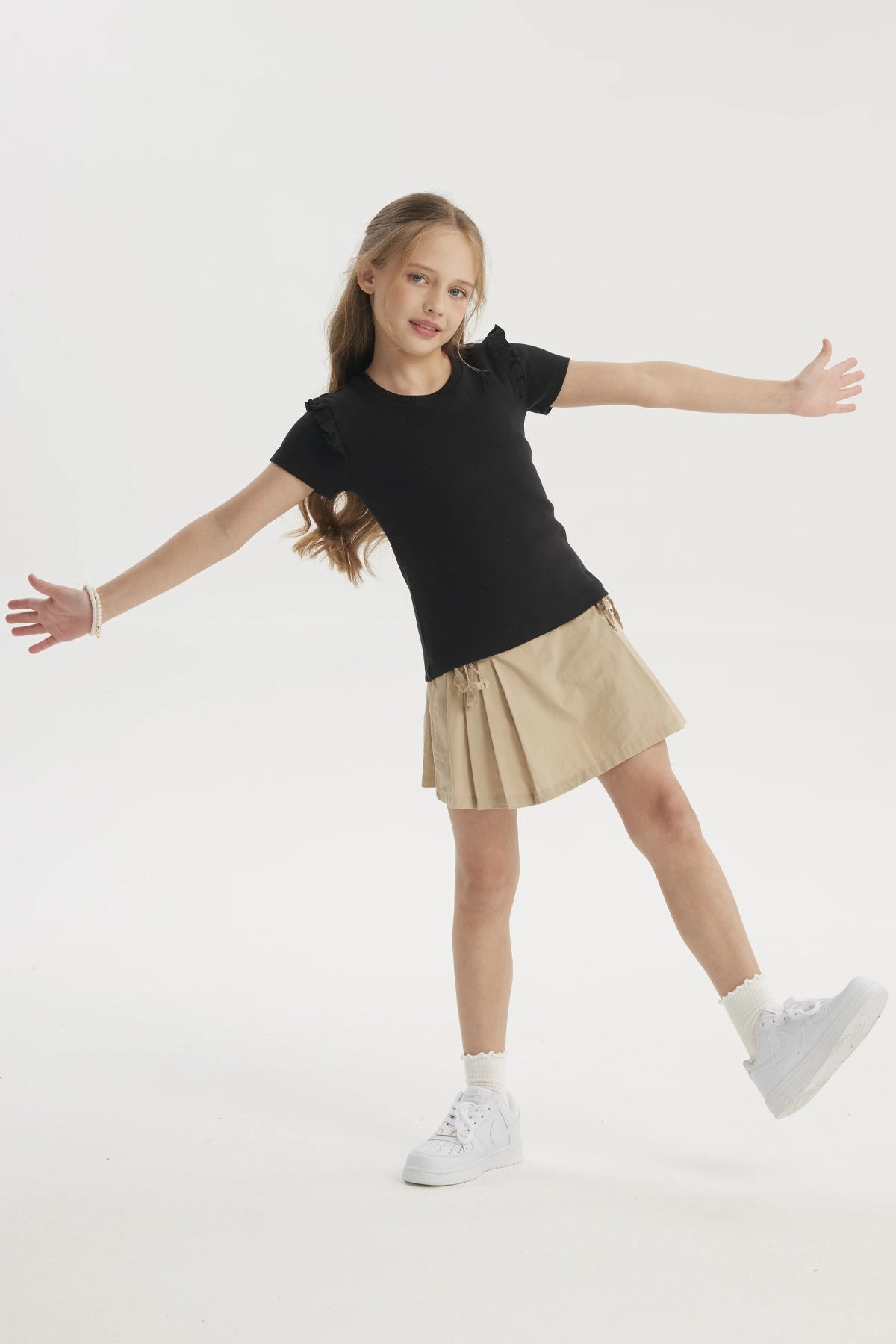 Polera negra para niña con vuelos en los hombros prenda lisa de algodón ideal para un look casual y cómodo