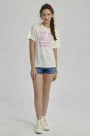 Polera cruda para niña con estampado gráfico en rosa de osito y frases Stay Cool en el pecho estilo casual y relajado