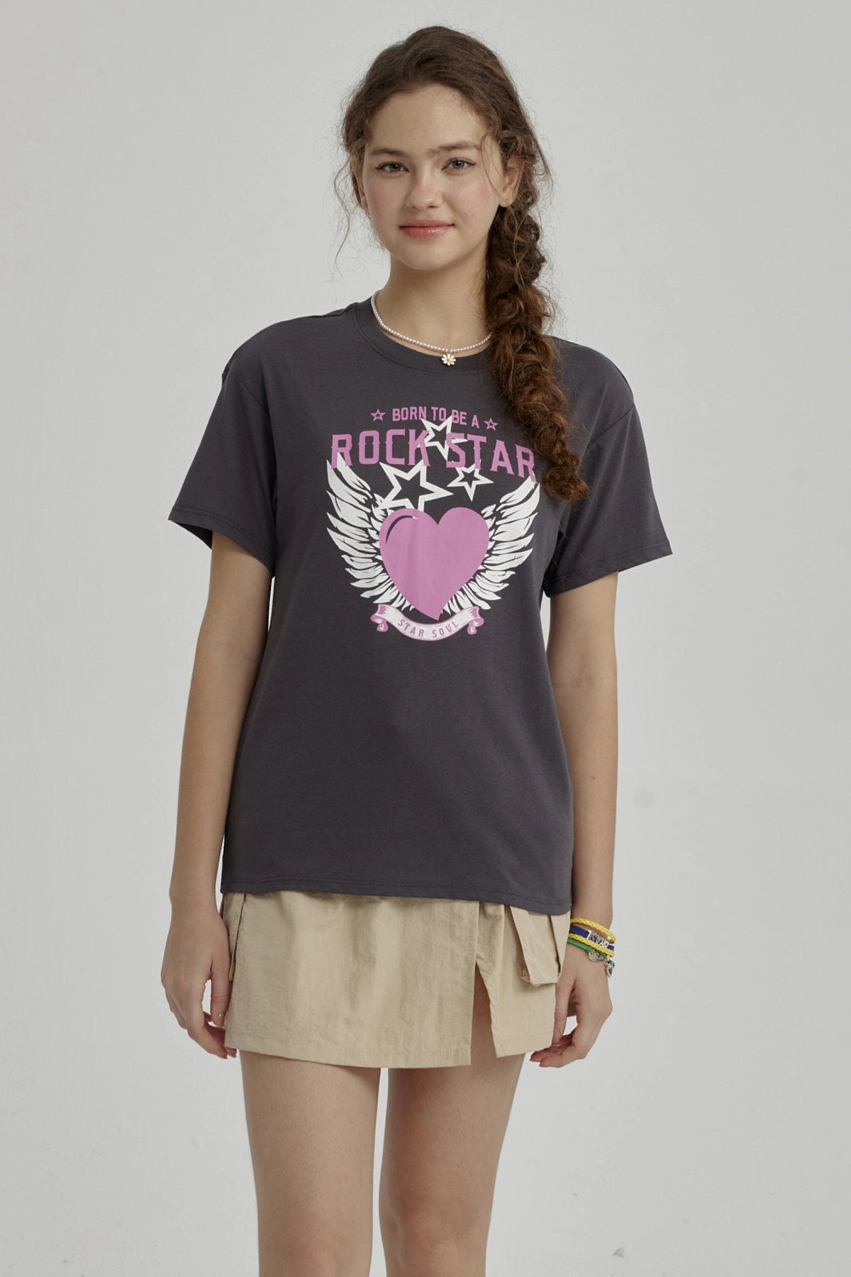 Polera niña gris oscuro con diseño de corazón rosa y alas blancas centrado en el pecho estilo gráfico