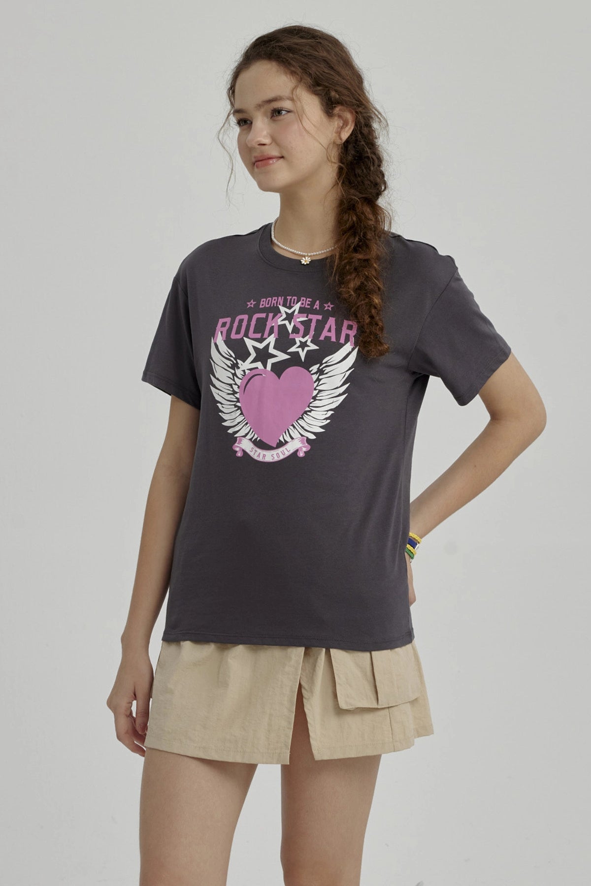 Polera niña gris oscuro con diseño de corazón rosa y alas blancas centrado en el pecho estilo gráfico