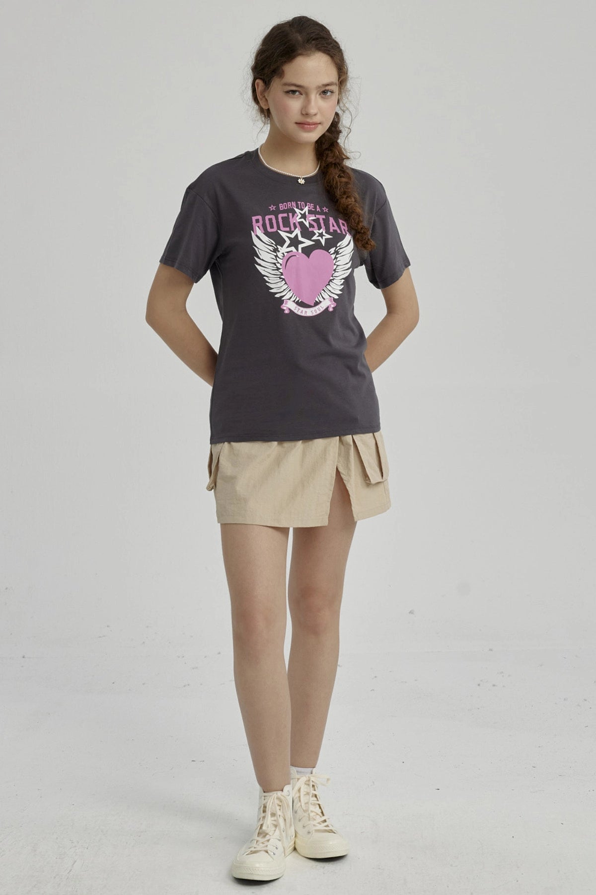 Polera niña gris oscuro con diseño de corazón rosa y alas blancas centrado en el pecho estilo gráfico