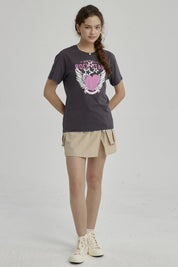 Polera niña gris oscuro con diseño de corazón rosa y alas blancas centrado en el pecho estilo gráfico
