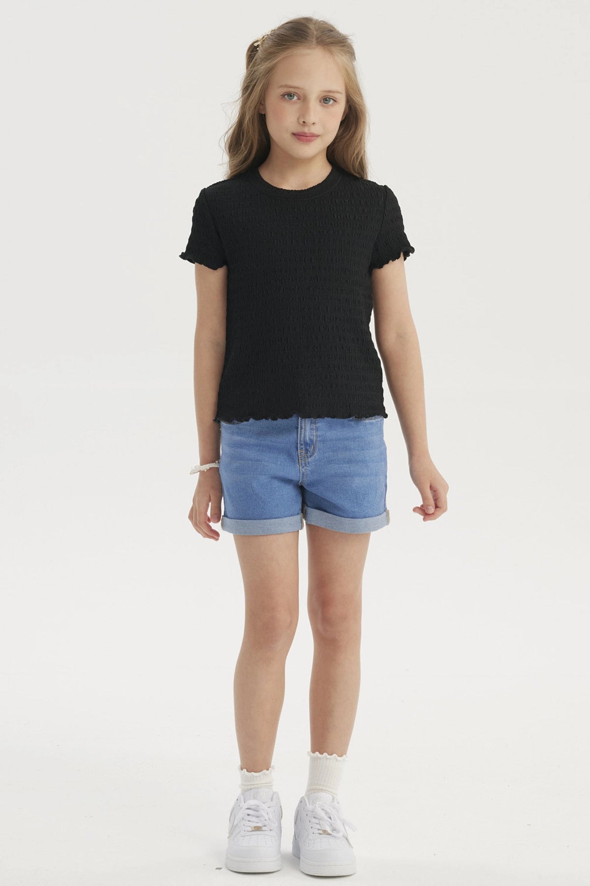 Polera negra para niña con textura lisa y mangas cortas onduladas ideal para un look casual y cómodo