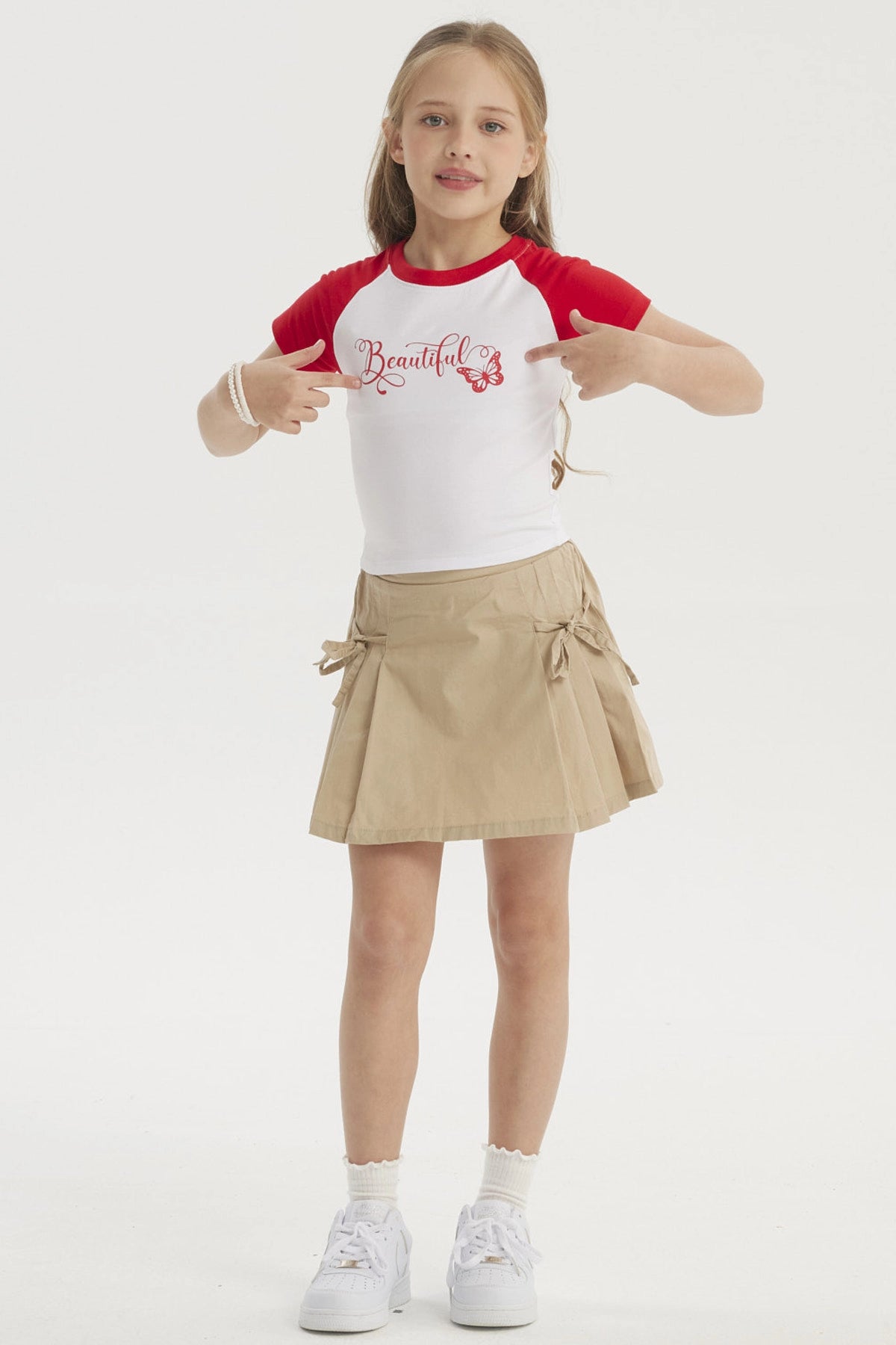 Falda beige de niña con pliegues laterales y lazos en la cintura diseño liso ideal para un look casual fresco