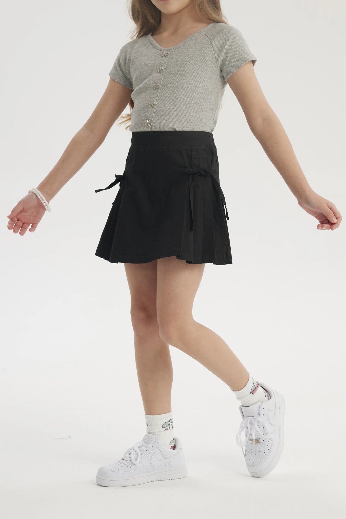 Falda negra para niña con pliegues laterales y lazo en la cintura diseño liso ideal para un look casual y cómodo