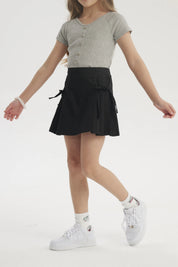 Falda negra para niña con pliegues laterales y lazo en la cintura diseño liso ideal para un look casual y cómodo