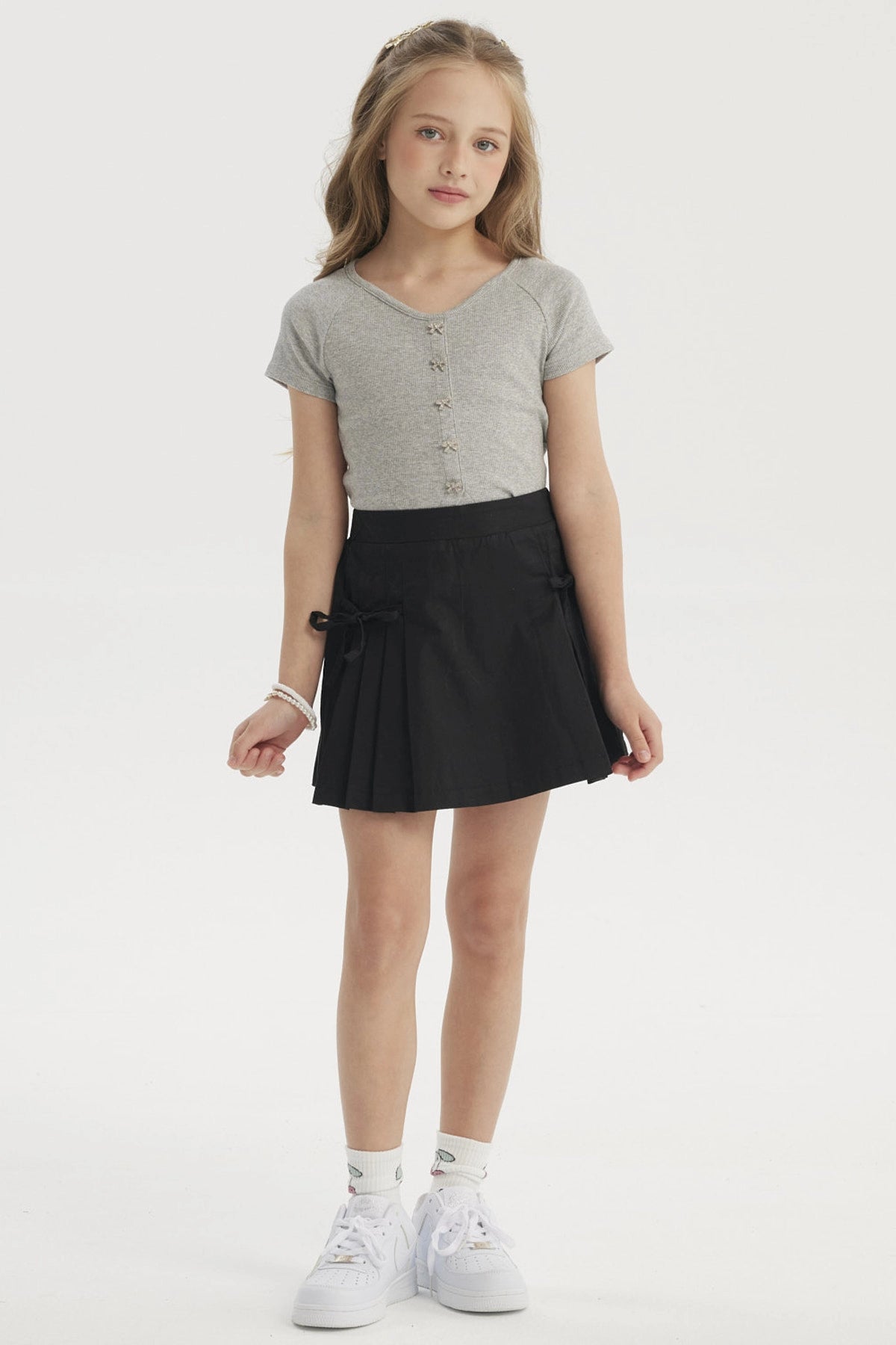 Falda negra para niña con pliegues laterales y lazo en la cintura diseño liso ideal para un look casual y cómodo