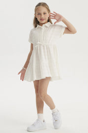 Vestido niña crudo con cuello redondo y mangas cortas detalle de lazo en cintura y diseño plisado liso